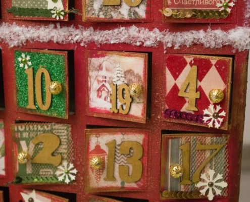 Auf dem Bild sind rot bemalte Holzschubfächer zu sehen. Die wilde Nummerierung lässt auf einen Adventskalender schließen.